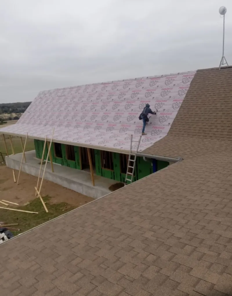 Worker preparing underlayment for a metal roof installation in Augusta